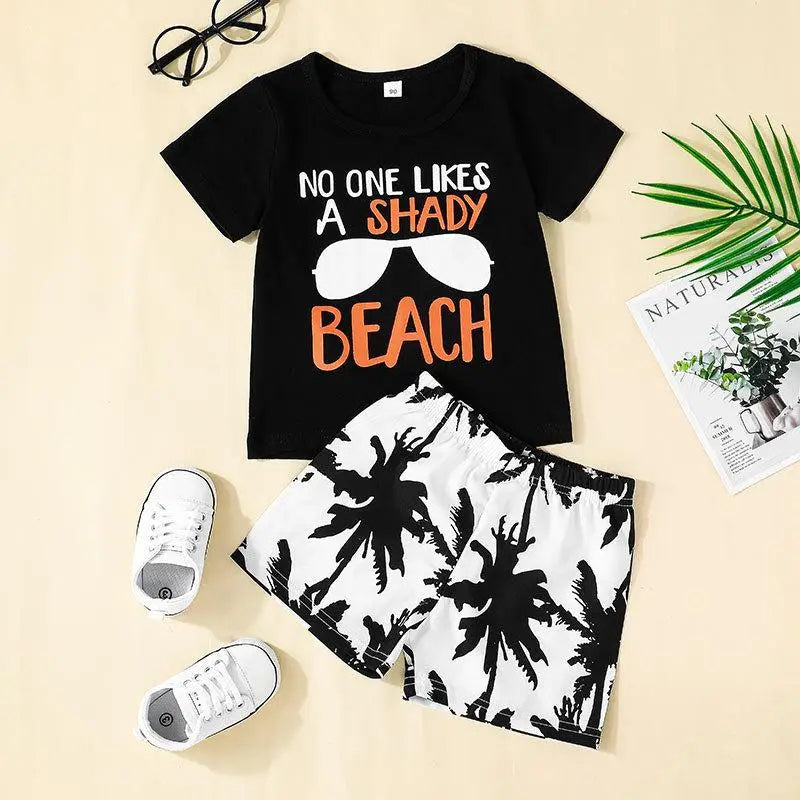 Two piece set for toddler boys with black and white palm print shorts and a black Y-shirt printed NO ONE LIKES A SHADY BEACH 